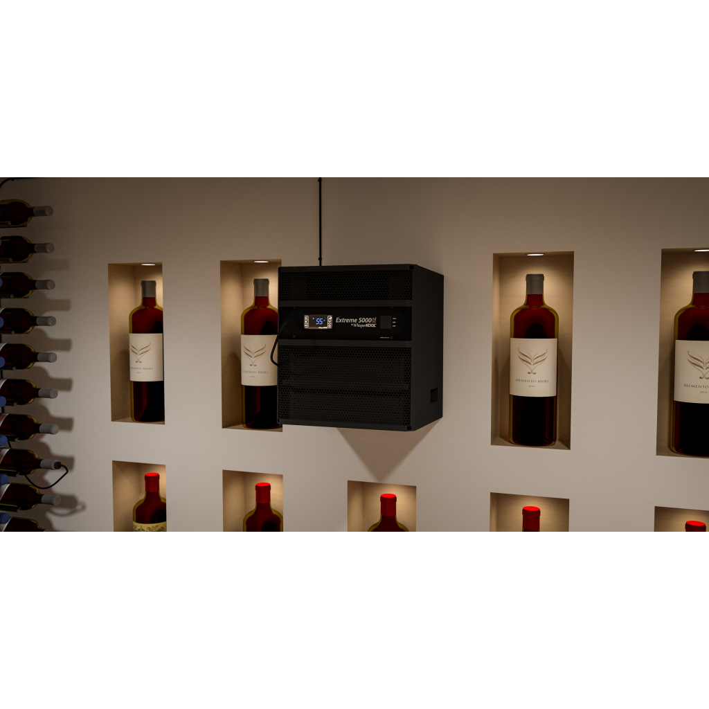 A WhisperKOOL Extreme 3500ti wine cellar cooling unit in black is mounted on the wall above recessed shelves displaying bottles of red wine.
