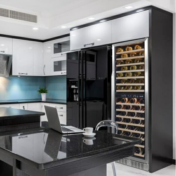 A black and white kitchen equipped with a NewAir 27” 160 Bottle Built-in Dual Zone Compressor Wine Fridge.