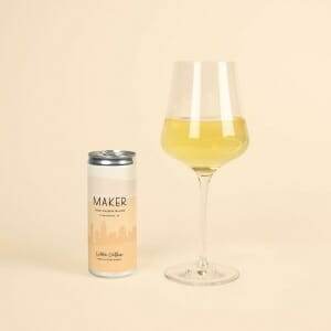 A glass of Maker Wine Chenin Blanc by Colleen Clothier next to a can of the same wine by Colleen Clothier.