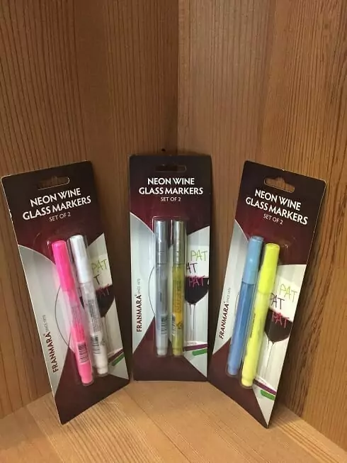 Three Neon Wine Glass Markers on a wooden table.