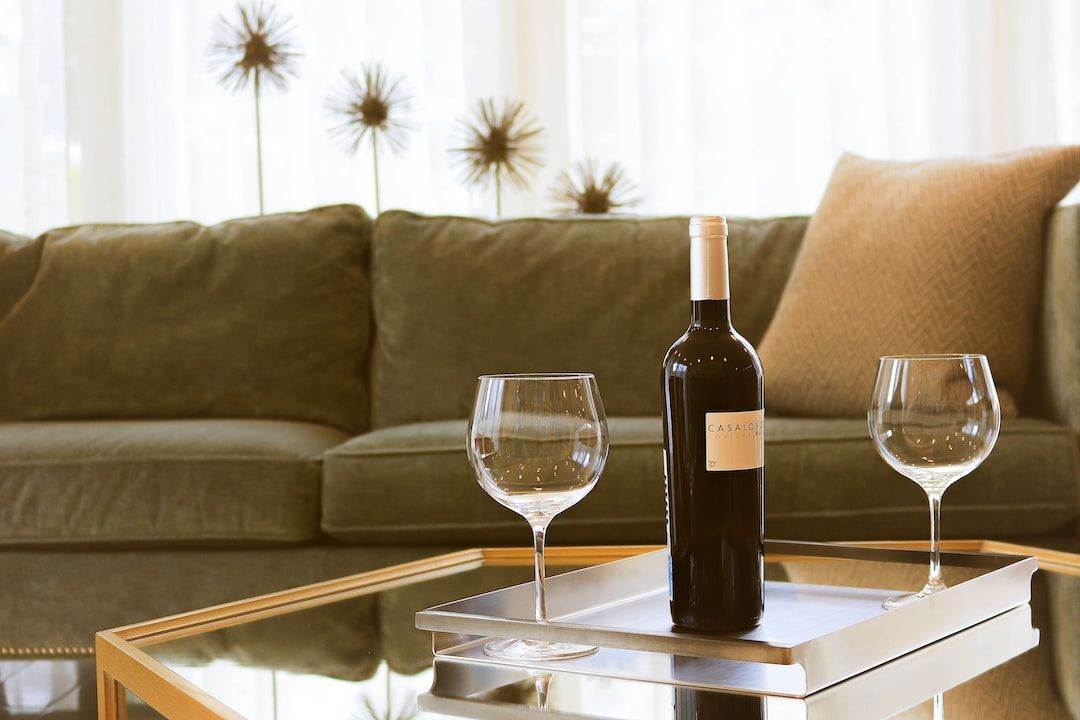 Two wine glasses and a bottle of wine on a table in front of a couch.
