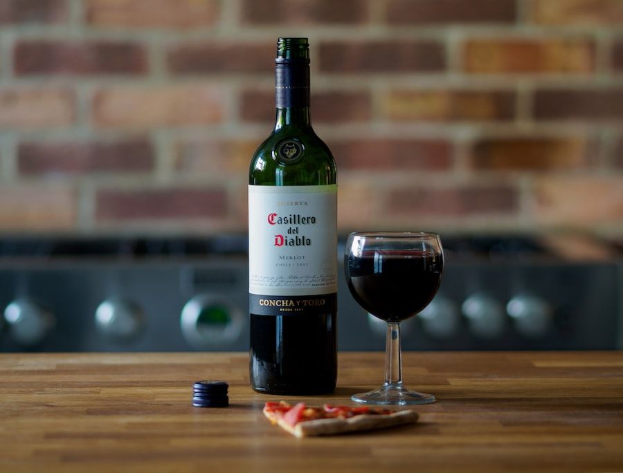 A bottle of red wine and a glass of wine on a table.