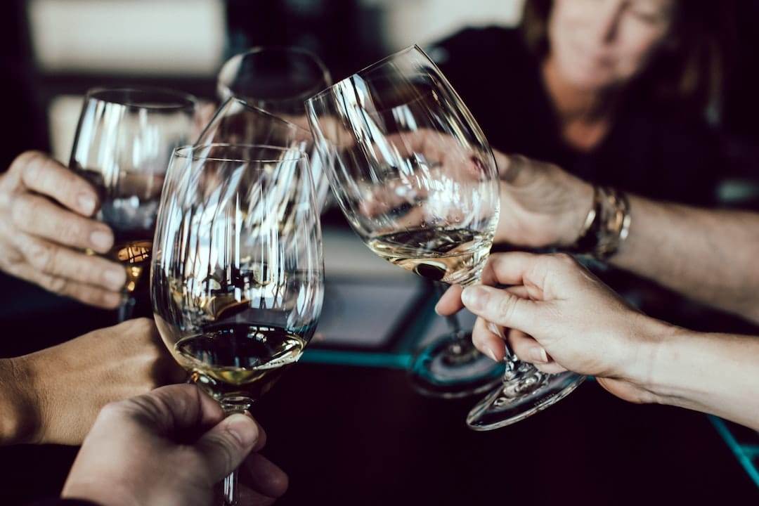 A group of people toasting wine glasses at a table.