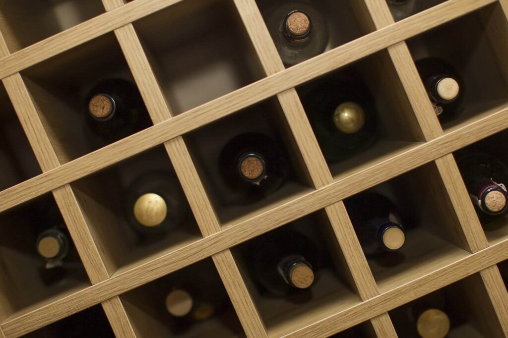 A space-saving wooden wine rack holds several bottles of wine, each stored horizontally in individual square compartments, making it an ideal addition to any home.