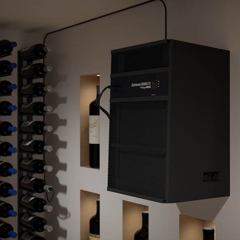 A black server unit labeled "Extreme 8000" is mounted on a wall in a wine cellar, surrounded by wine bottles stored in wall racks and shelves.