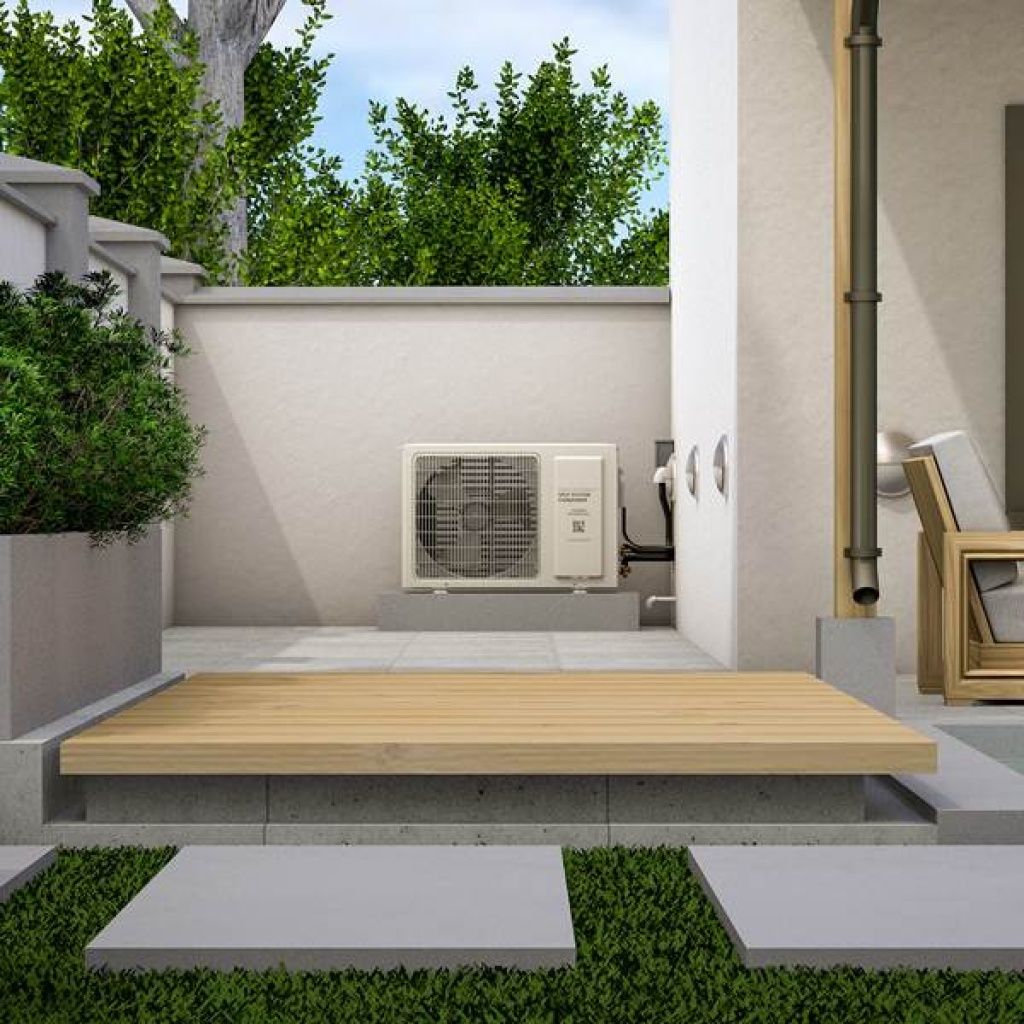 A modern outdoor space with a wall-mounted air conditioner unit, a small wooden deck, a lounge chair, and surrounding greenery.