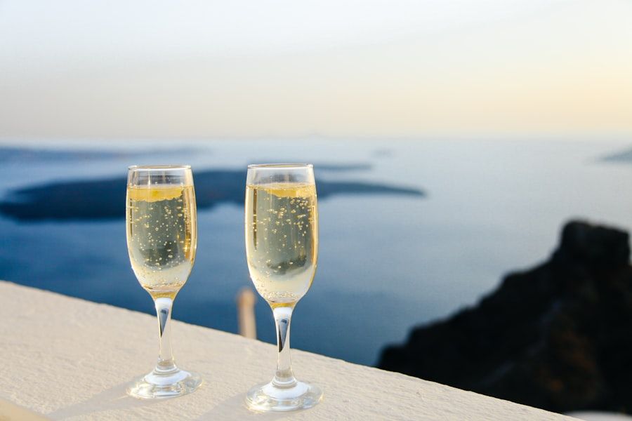 Two glasses of champagne sit on a ledge with a scenic ocean view in the background.