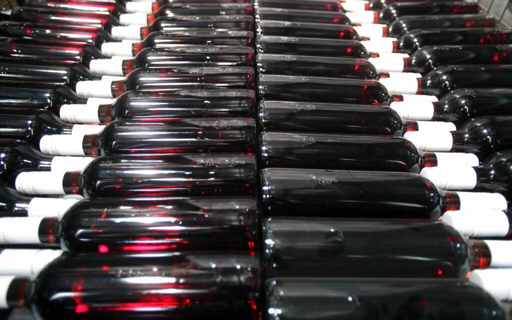 Rows of horizontally stacked wine bottles with dark liquid, white caps, and visible reflections present an elegant storage solution for San Francisco apartments. This clever arrangement offers a stylish touch to wine cellar ideas even in small space solutions.