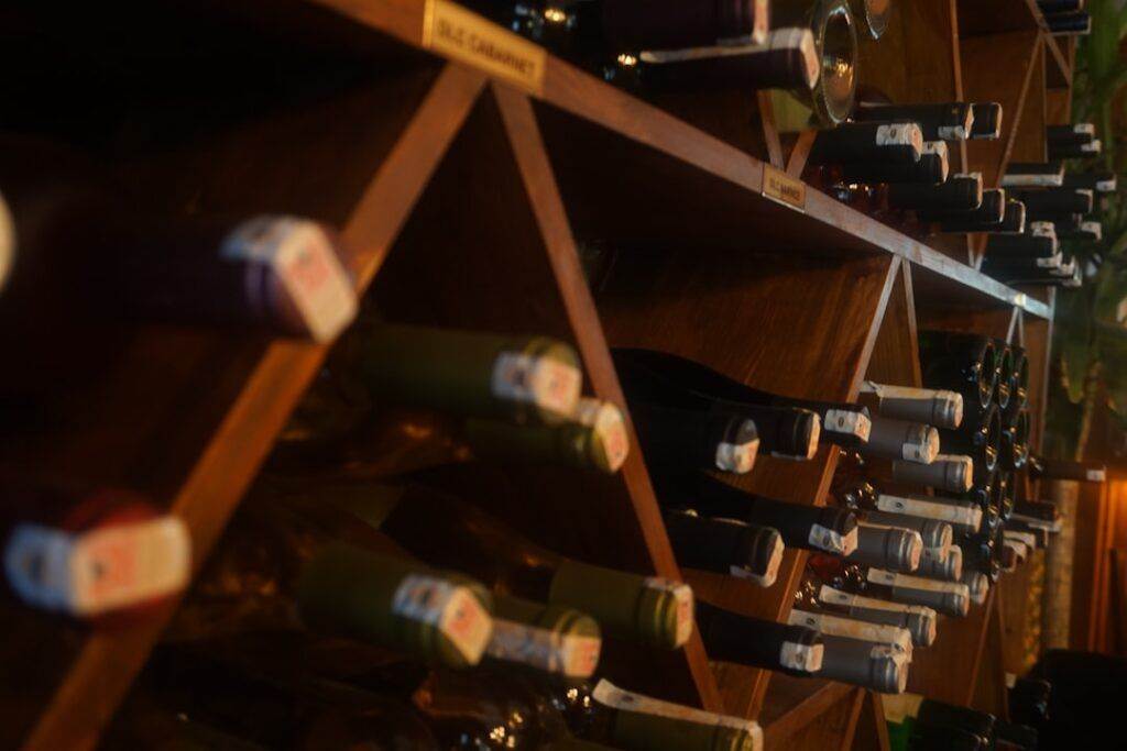 A wine rack filled with various bottles, viewed from a lower angle, displaying an array of bottle tops.