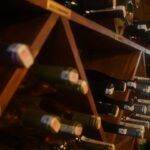 A wine rack filled with various bottles, viewed from a lower angle, displaying an array of bottle tops.