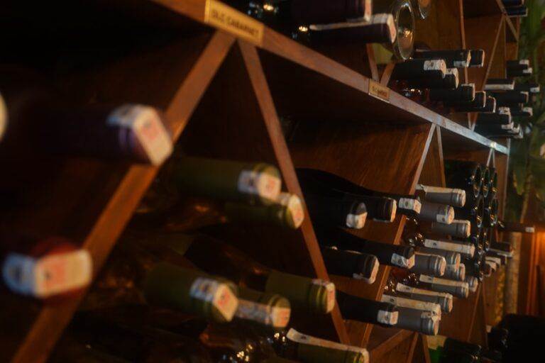 A wine rack filled with various bottles, viewed from a lower angle, displaying an array of bottle tops.