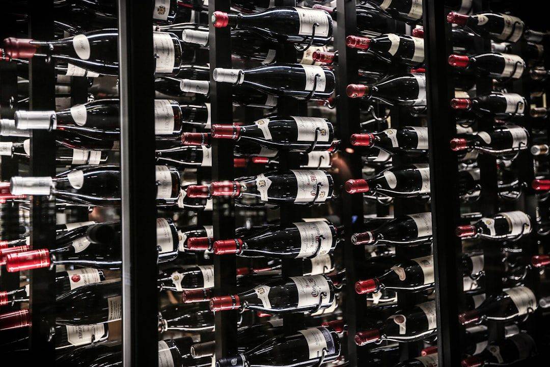 Rows of wine bottles stored horizontally in a temperature-controlled cellar with dark shelves.