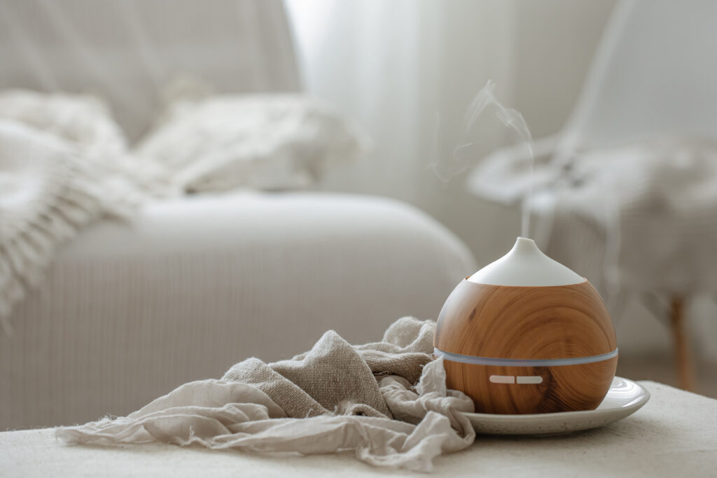 A round wood-grain essential oil diffuser emits vapor, improving cellar humidity as it sits on a cloth in a softly lit, cozy room.