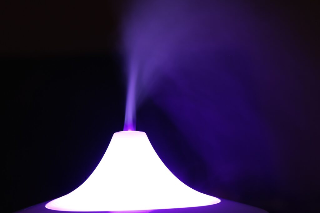 A cone-shaped diffuser emits visible mist, illuminated by purple light against a dark background—an elegant touch for any space, from a walk-in pantry to a climate-controlled wine cabinet.