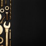 Assorted gold-colored tools and hardware, including wrenches, screws, bolts, and washers—perfect for work on San Francisco apartments—arranged vertically on the left side against a black background.