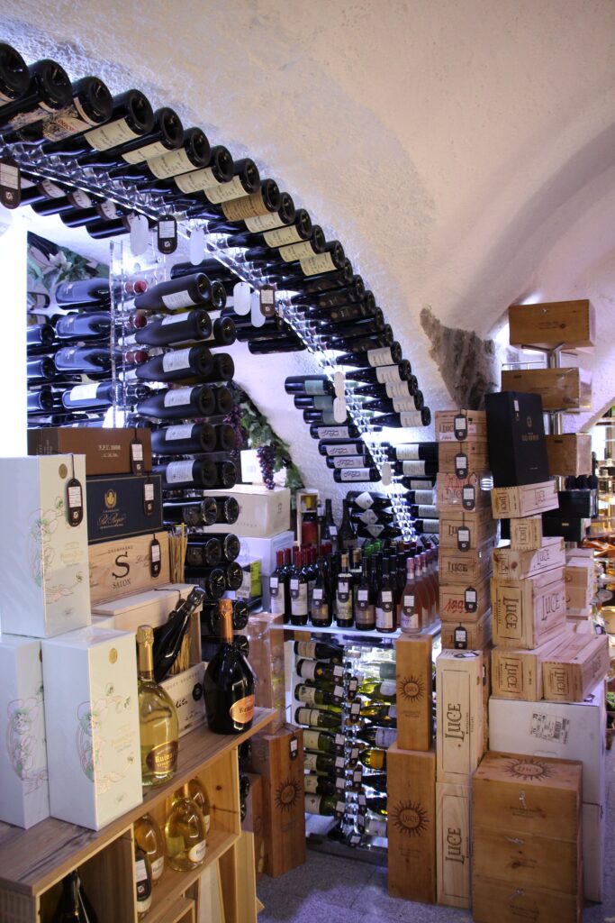 Wine cellar with arched racks holding bottles, surrounded by stacked wooden wine crates and boxes under a vaulted ceiling—ideal for proper cellar humidity and easy cellar maintenance.