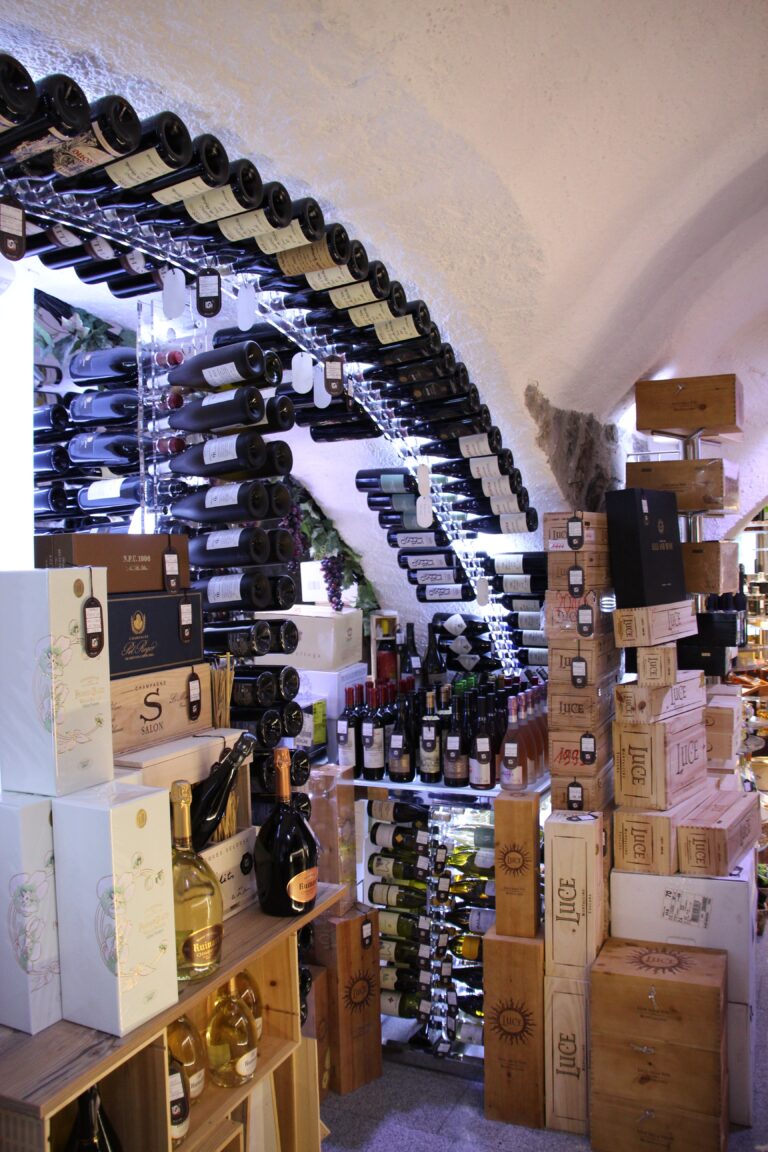 Wine cellar with arched racks holding bottles, surrounded by stacked wooden wine crates and boxes under a vaulted ceiling—ideal for proper cellar humidity and easy cellar maintenance.