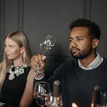 Two adults sitting at a table enjoying a sophisticated wine tasting experience.