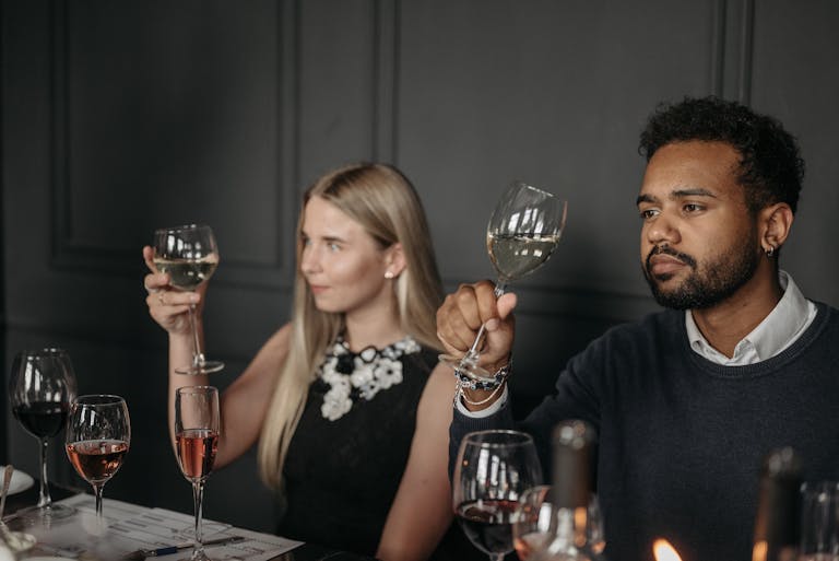 Two adults sitting at a table enjoying a sophisticated wine tasting experience.