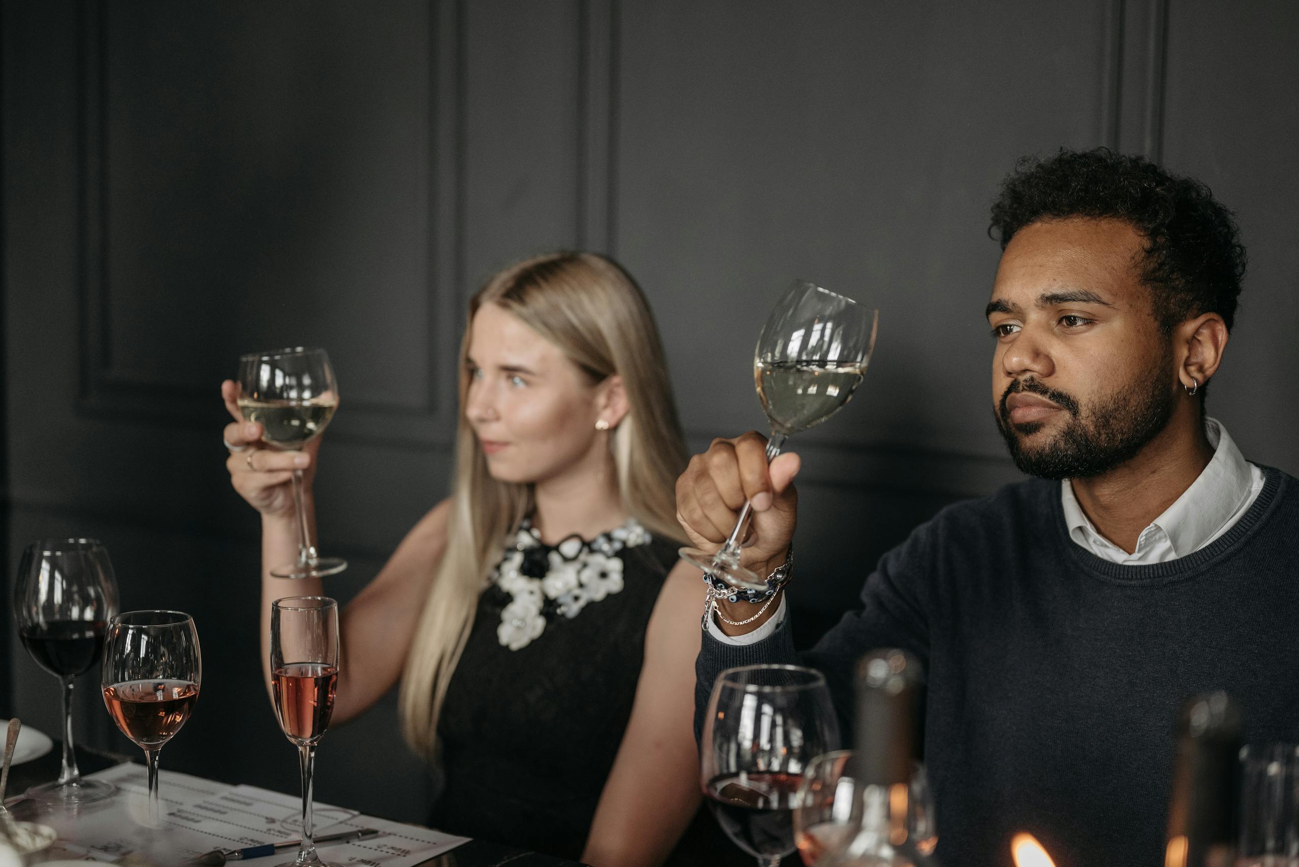 Two adults sitting at a table enjoying a sophisticated wine tasting experience.